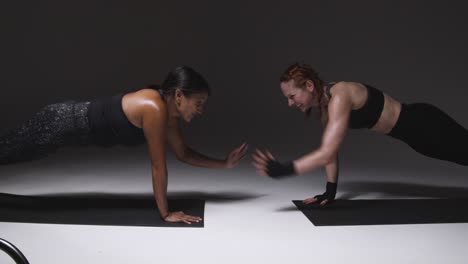 Studioaufnahme-Von-Zwei-Reifen-Frauen-In-Fitnesskleidung,-Die-Gemeinsam-Plankenübungen-Machen-1